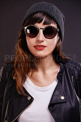 Buy stock photo Confident, woman and punk fashion in studio for trendy rocker style with sunglasses. Bold, female person and leather clothes for creative skin tattoo, art decoration and grunge by dark background
