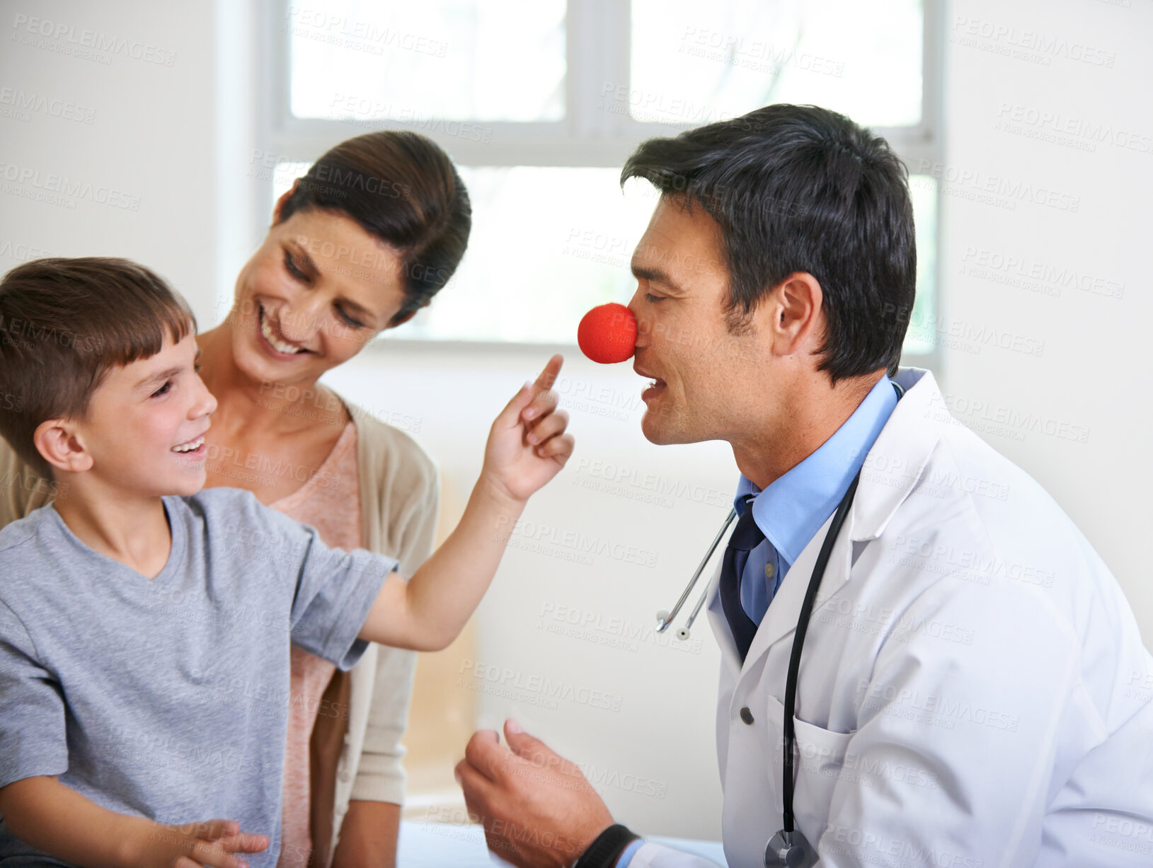 Buy stock photo Healthcare, red nose and pediatrician with family in hospital for appointment, distraction or medical. Clown, smile or trust with doctor, mom and son in clinic for checkup, consulting or playful fun