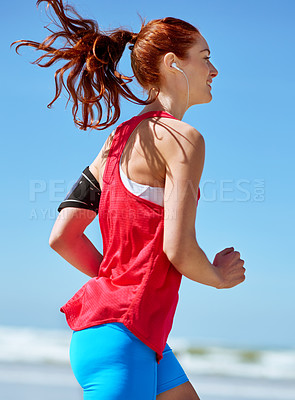 Buy stock photo Fitness, music and running with woman on beach in morning for cardio, exercise or marathon training. Sky, smile and streaming with athlete runner outdoor in summer for sports improvement or wellness