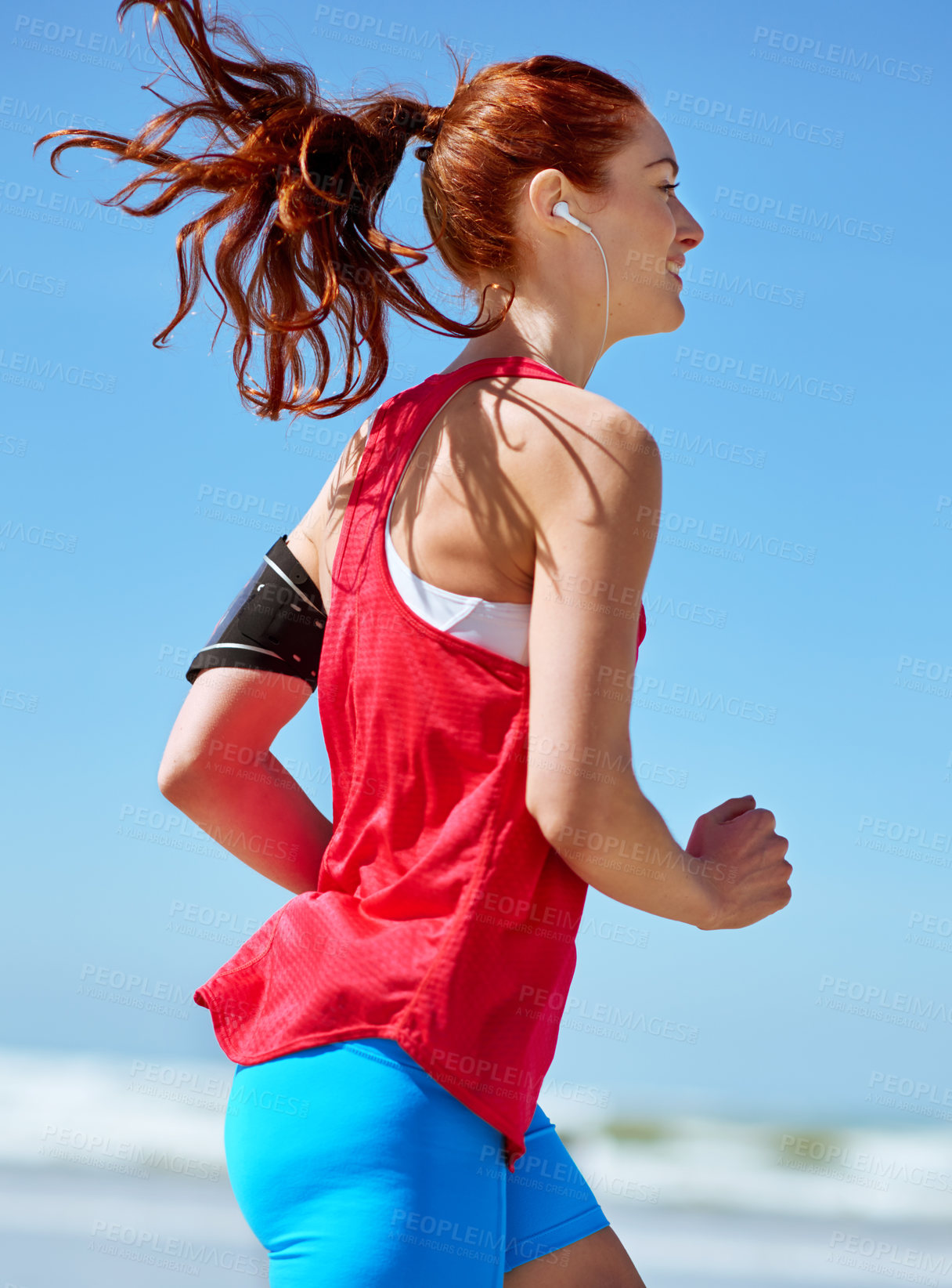 Buy stock photo Fitness, music and running with woman on beach in morning for cardio, exercise or marathon training. Sky, smile and streaming with athlete runner outdoor in summer for sports improvement or wellness