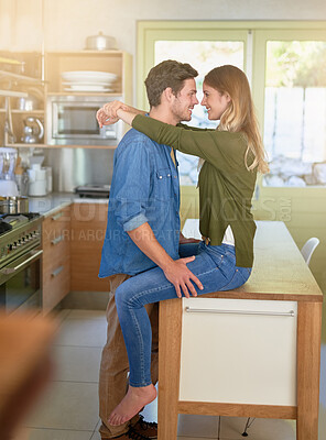 Buy stock photo Shot of an affectionate young couple hugging in their kitchen