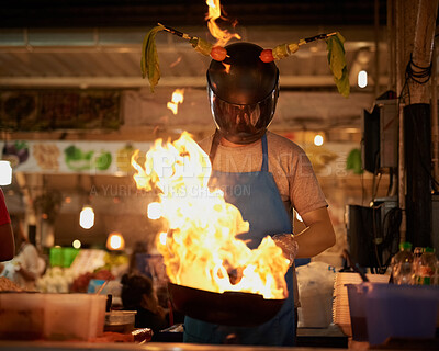 Buy stock photo Food, vendor and pan with hot fire, helmet and flames for cooking, service and meal as startup in Asia. Entrepreneur, person and work as small business with flambe, hibachi and cuisine in kitchen