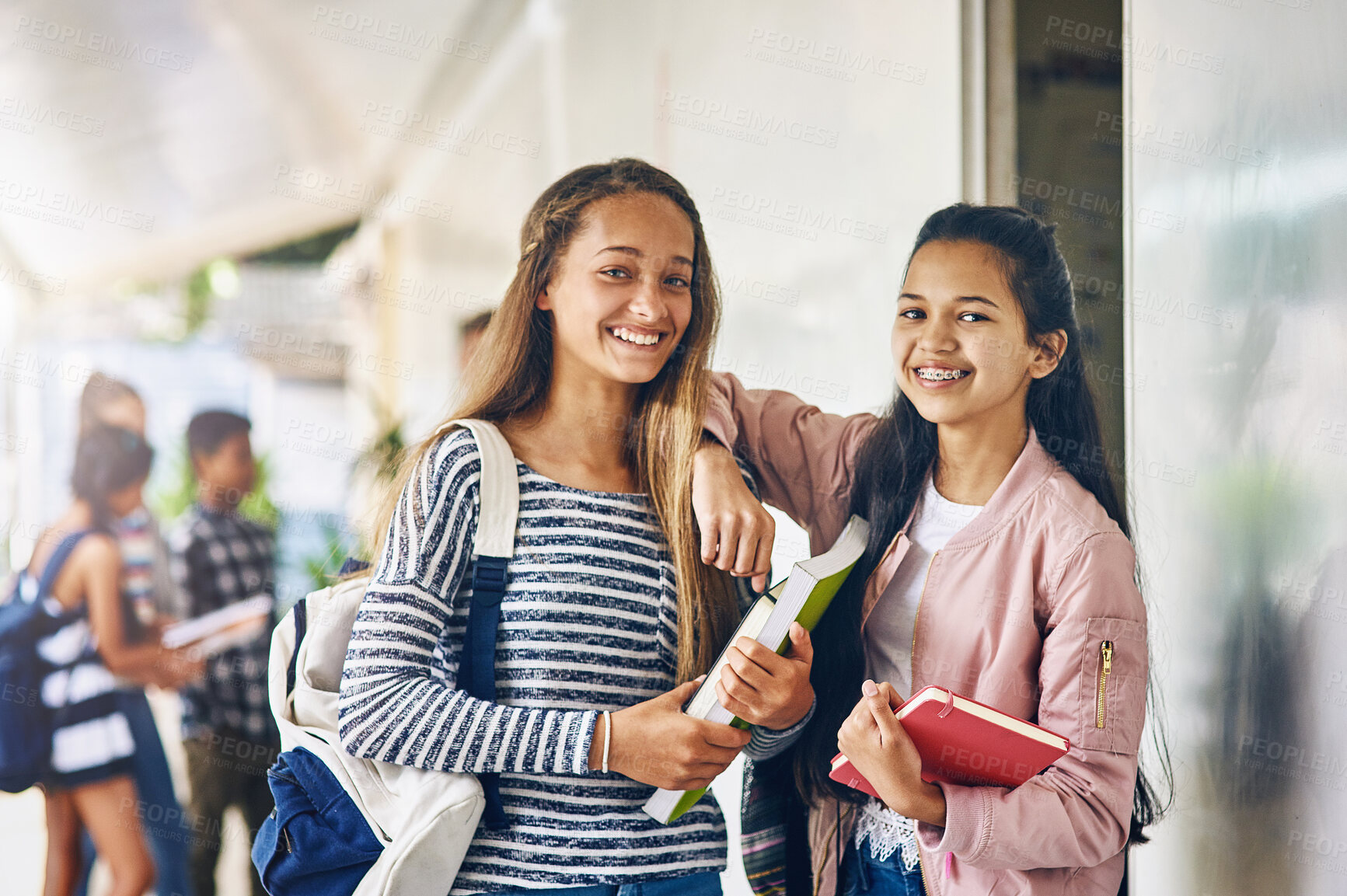 Buy stock photo Portrait of two happy schoolgirls standing together in the hallway outside their classroom