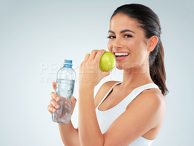 Buy stock photo Portrait, apple and model with water in studio for nutrition, diet or lose weight on blue background. Healthy body, bottle and happy woman with fruit for fitness, workout goals or digestion benefits