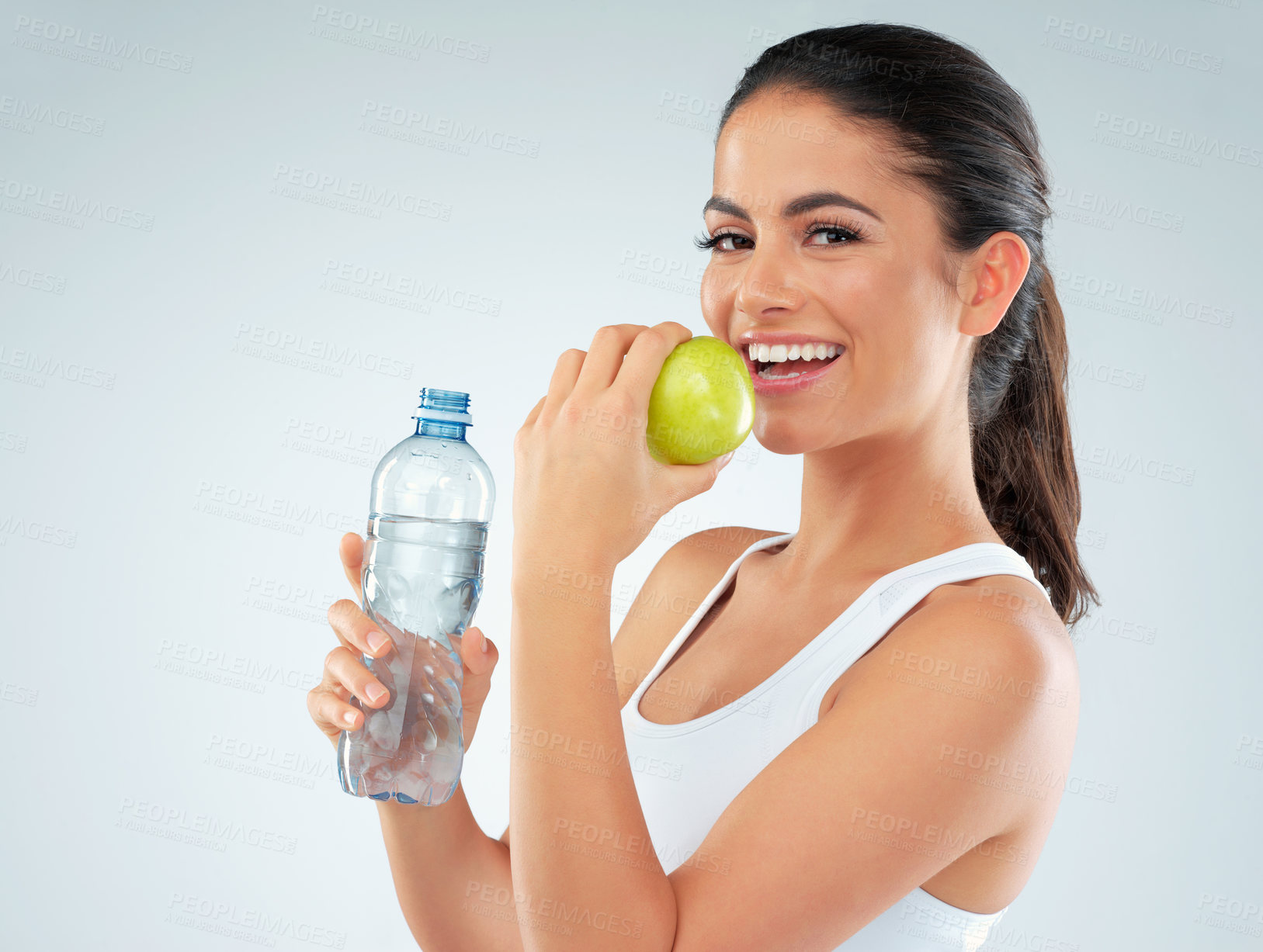 Buy stock photo Portrait, apple and model with water in studio for nutrition, diet or lose weight on blue background. Healthy body, bottle and happy woman with fruit for fitness, workout goals or digestion benefits