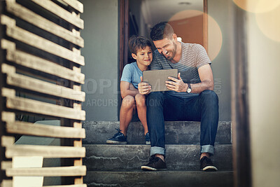 Buy stock photo Shot of a father and son using a digital tablet together on the front steps of their home