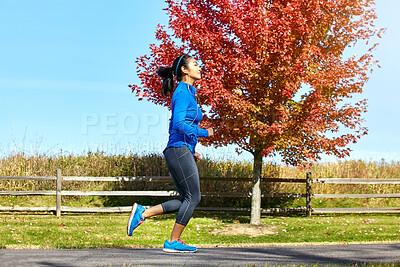 Buy stock photo Happy woman, running and fitness with earphones for exercise, music or podcast in countryside. Active female person, young athlete or runner with audio, sound or cardio for outdoor workout in nature