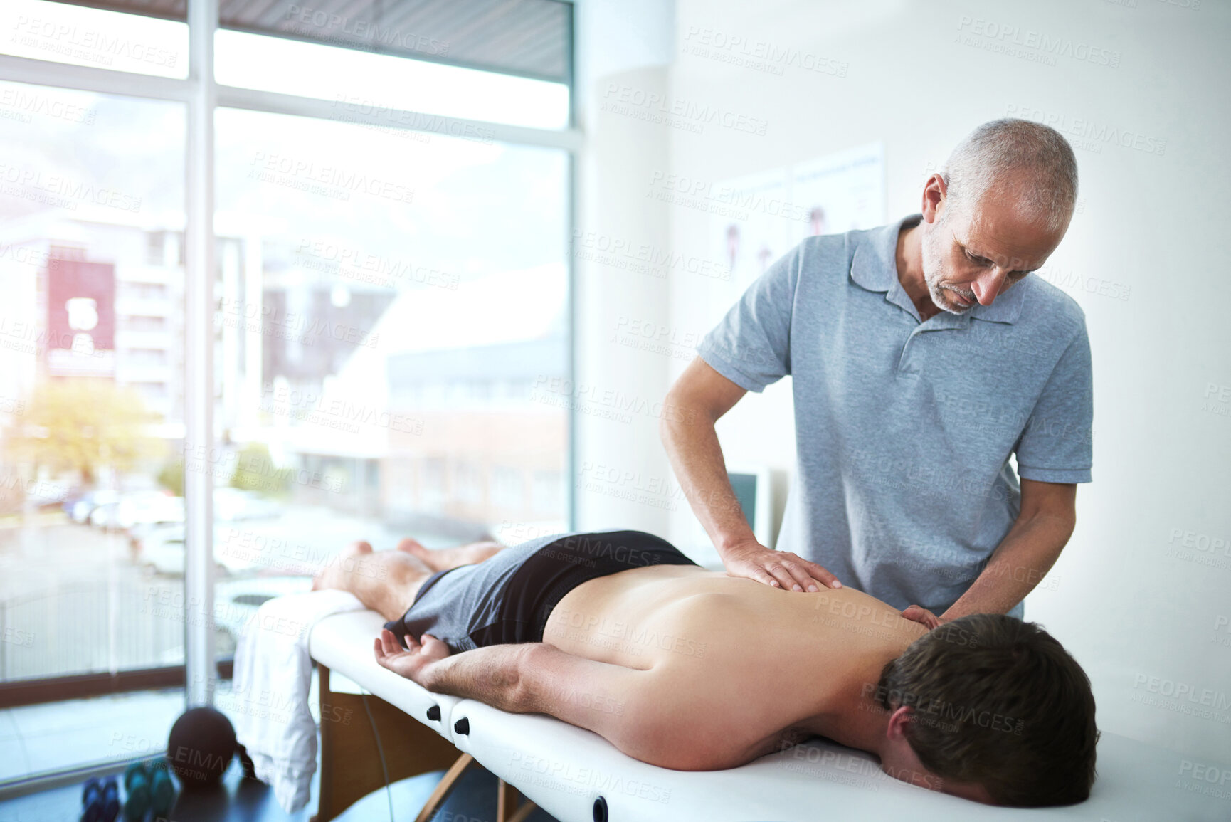 Buy stock photo Man, back support and physiotherapist consulting or working, rehabilitation and exercise for wellness. Male people, office and together for physiotherapy service with health insurance or muscle pain