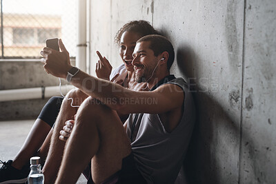 Buy stock photo Couple, health and exercise break with phone for fitness podcast, streaming in building for wellness. Man, woman or mobile app for workout together with rest in parking lot, music for gym or training