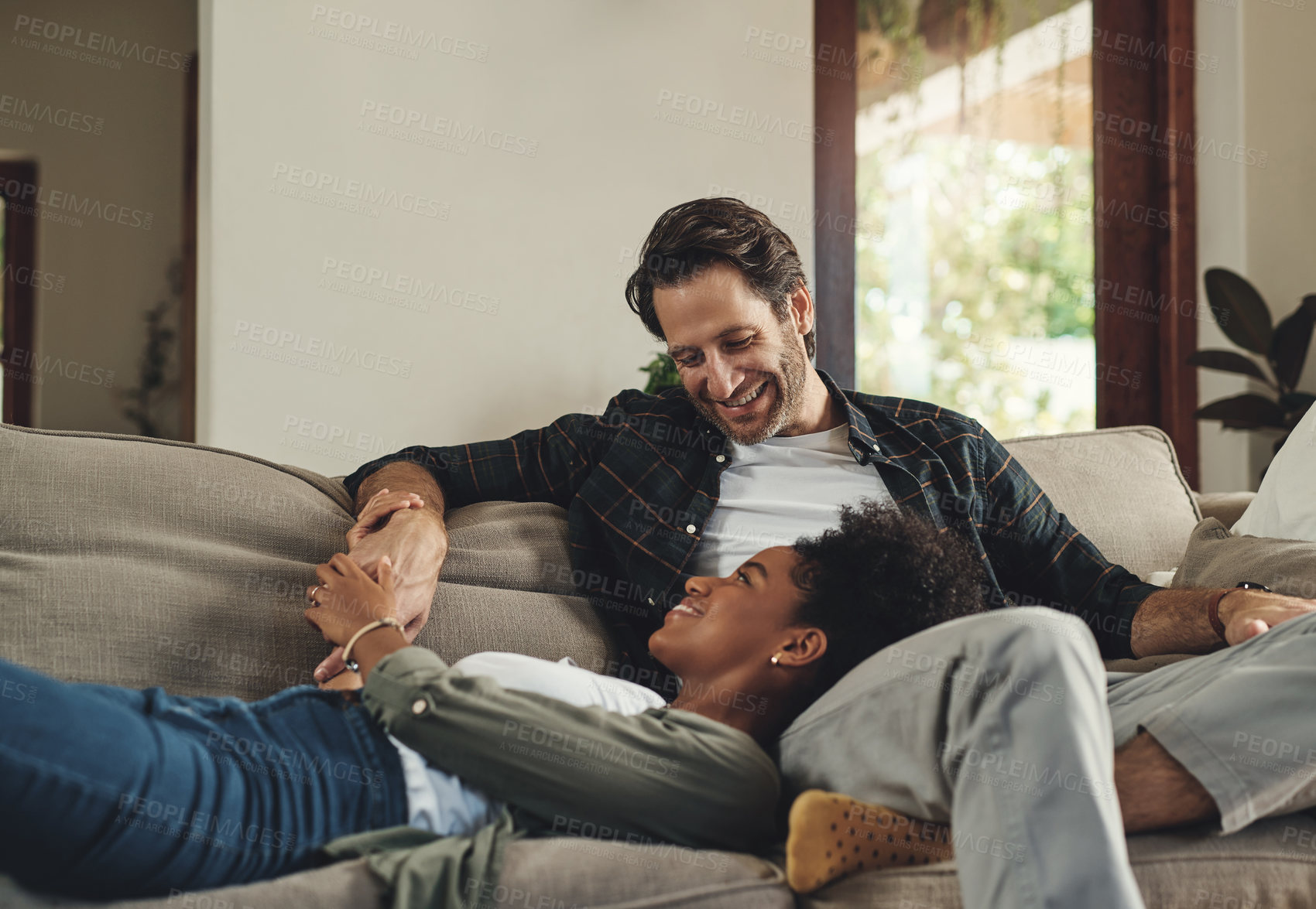 Buy stock photo Happy couple, interracial and relax together on couch for romantic time, love and bonding in home. Smile, man and black woman in lounge with healthy relationship, support and commitment for marriage