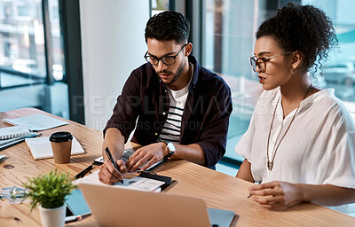 Buy stock photo Cropped shot of two young businesspeople sitting together and having a meeting over polaroids in the office