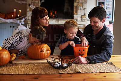 Buy stock photo Shot of an adorable young family carving out pumpkins and celebrating halloween together at home