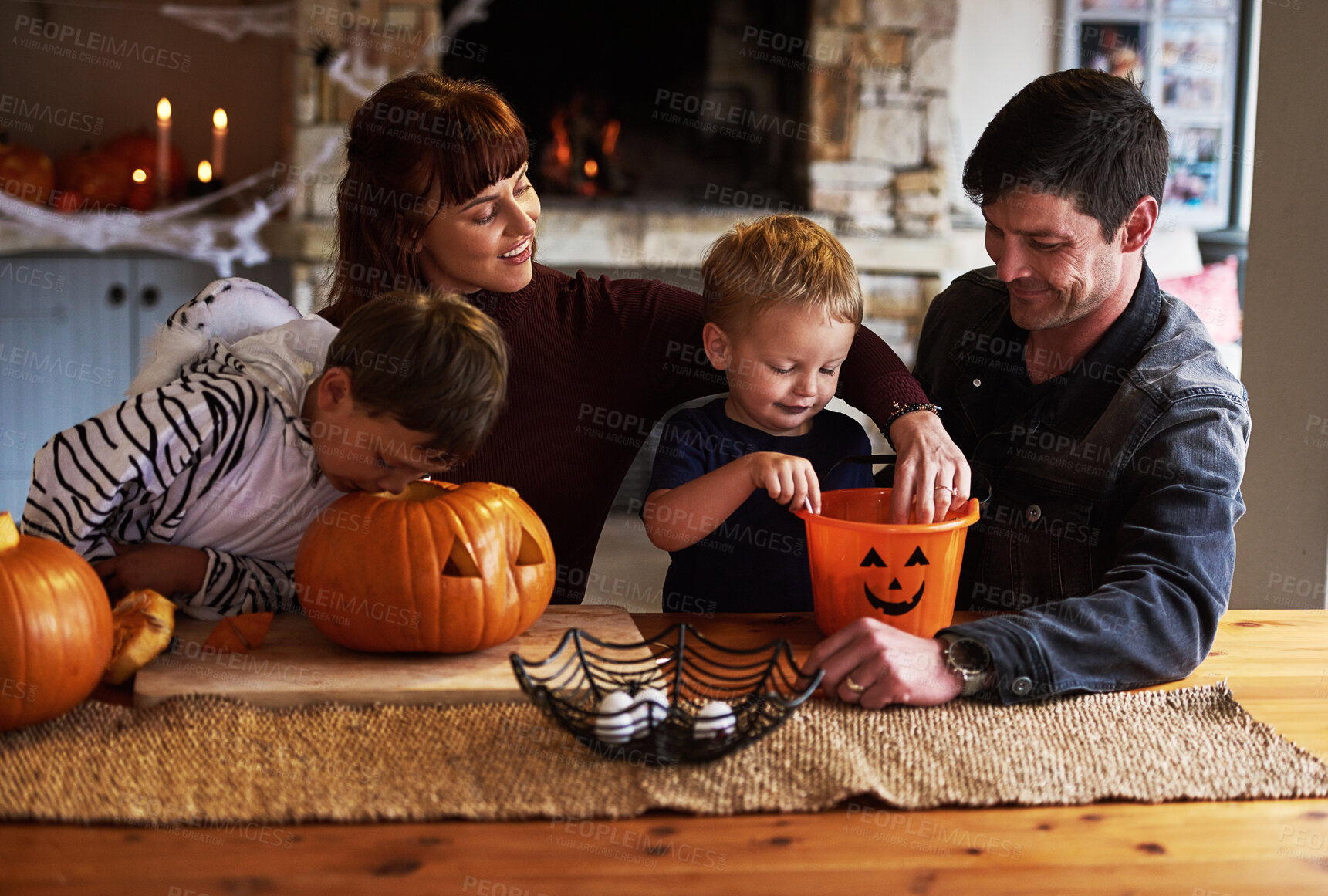 Buy stock photo Shot of an adorable young family carving out pumpkins and celebrating halloween together at home