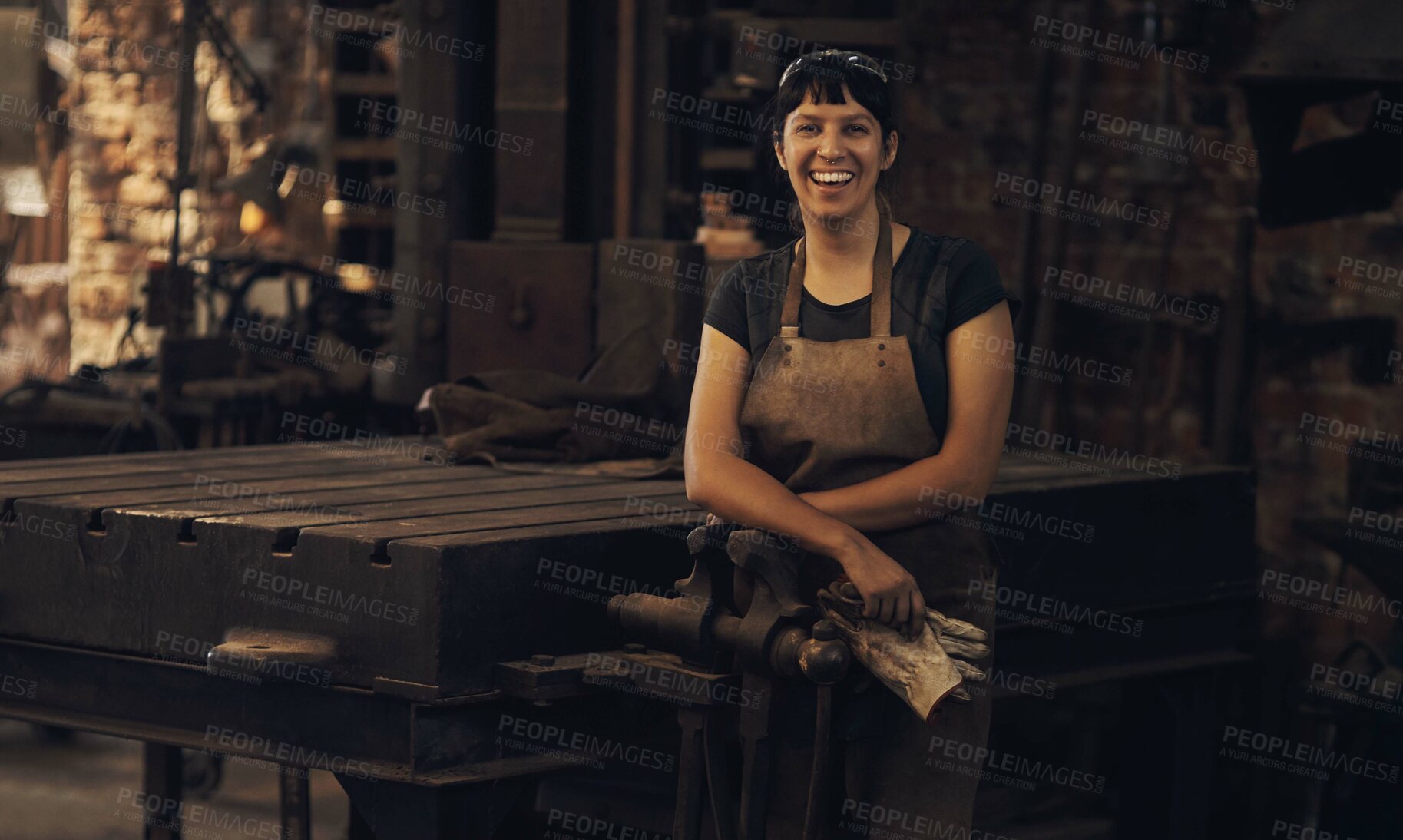 Buy stock photo Portrait, gloves and woman with smile, workshop and proud of gender equality in foundry and blacksmith. Hardworking, apron and manufacturing in factory, person and skills for welding and dark