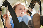 Adorable little caucasian girl having fun while sitting on swing at park. Energetic child playing on outdoor playground on a sunny day.