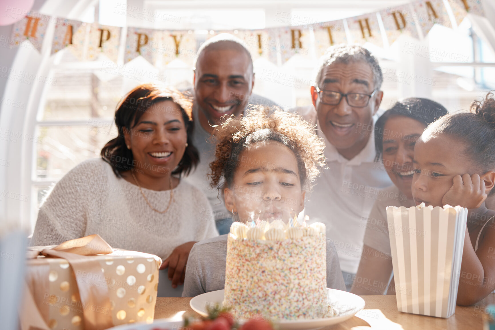 Buy stock photo Girl, birthday cake and blowing candles with family for fun together, happiness and annual milestone in home. Child, event or party for celebration of growth with gift, dessert food and generations