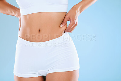 Buy stock photo Fitness, health and woman pinch abdomen in studio with wellness, exercise and weightloss for slim body. Underwear, detox and female person touch stomach for workout by blue background with mockup.