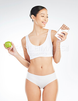 Buy stock photo Decisions, woman and apple or chocolate in studio with choice for healthy snack, nutrition benefits and balance diet. Female person, food and fruit for breakfast, challenge and white background