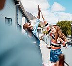 A cheerful african american man doing a high five gesture with a mixed race woman while smiling and laughing outside on a sunny day while enjoying a drink of beer in a glass bottle. Black male and his hispanic friend having fun and celebrating at a party