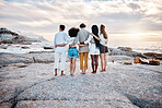 Rear view of a Unknown group of friends enjoying their time together at the beach. Diverse group of friends huddling outdoors