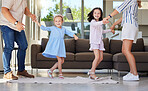 Excited happy kids having fun with energetic young parents at home. Sisters dancing together with mom and dad. Family having fun dancing to music