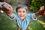 The moment of lifting the son up holding his hands by mom and dad while outside in the backyard. Young happy boy having fun and smiling while being lifted by two hands on a sunny day
