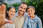 Family selfie in the garden at home. Young family of three snapping pictures while outside in the yard. Handsome man, beautiful woman and cute son taking photographs outside