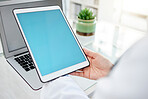 Unknown mixed race woman using a tablet and typing a email while sitting at her desk in a hospital. Female doctor using a wireless device while working