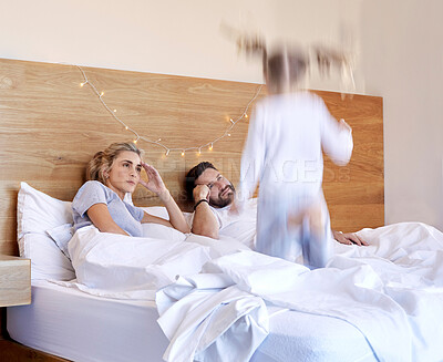 Buy stock photo Parents, bed and tired from jumping child, adhd and chaos in home bedroom on weekend. Excited, energy and girl with motion blur for speed, headache and stress or overwhelmed man and female person 