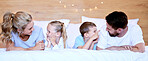 Happy carefree caucasian family lying cosy on bed while bonding together at home. Loving parents spending quality time with little son and daughter. Cute kids enjoying lazy morning with mom and dad