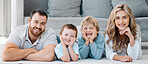 Portrait of smiling caucasian family of four lying and relaxing on the floor at home. Carefree loving parents bonding with cute little sons. Playful young boys spending quality time with mom and dad