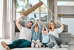 Smiling couple with little kids sitting and making symbolic roof with cardboard over children. Caucasian brothers protected by parents. Mother and father covering their sons with family care insurance