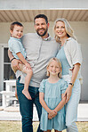 Portrait of happy parents and their two little children standing outside in a garden. Smiling caucasian couple bonding with their adorable son and daughter in the backyard. Cute brother and sister