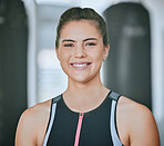 Portrait of one smiling woman alone in gym. Beautiful happy caucasian trainer standing after workout in health club. Young confident and cheerful coach in fitness centre for routine training exercise