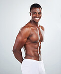 Portrait of a smiling African American fitness model posing topless in a underwear and looking muscular. Happy black male athlete isolated on grey copyspace in a studio wearing boxers