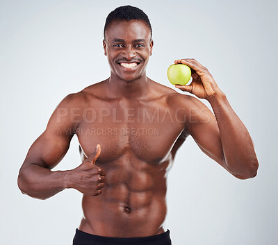 Buy stock photo Apple, thumbs up and portrait of black man in studio for diet, health and wellness for balance with nutrition. Muscles, snack and African person with approval gesture for fruit by white background.