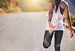 Close up of african american female athlete stretching before a run outside on a road. Exercise is good for your health and wellbeing. Stretching is important to prevent injury