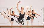 Young woman dance instructor teaching a ballet class to a group of a children in her studio. Ballerina teacher working with girl students, preparing for their recital, performance or upcoming show