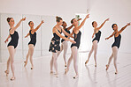 Young woman dance instructor teaching a ballet class to a group of a children in her studio. Ballerina teacher working with girl students, preparing for their recital, performance or upcoming show