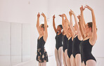 Young woman dance instructor teaching a ballet class to a group of a children in her studio. Ballerina teacher working with girl students, preparing for their recital, performance or upcoming show