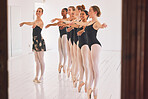 Young woman dance instructor teaching a ballet class to a group of a children in her studio. Ballerina teacher working with girl students, preparing for their recital, performance or upcoming show