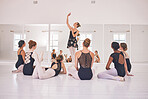 Young woman dance instructor teaching a ballet class to a group of a children in her studio. Ballerina teacher working with girl students, preparing for their recital, performance or upcoming show