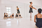 Young woman dance instructor teaching a ballet class to a group of a children in her studio. Ballerina teacher working with girl students, preparing for their recital, performance or upcoming show