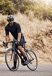  Athletic young man cycling on a mountain road. Sporty fit male cyclist wearing helmet and glasses while riding a bike for exercise. Sportsman training or doing a cardio workout