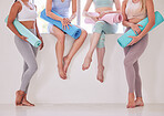 Feet of women in yoga class. Group of women ready for yoga class cropped. Peaceful friends relaxing before yoga class in the studio. Women holding exercise equipment in yoga class