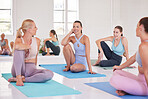 Group of women bonding in yoga class. Group of friends sitting on the floor in pilates class. Group of friends relaxing in yoga class. Happy friends sitting on mats in yoga class