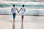 Happy african American couple spending a day at the sea together. Rearview of a cheerful boyfriend and girlfriend running into the water on the beach. Loving husband and wife bonding on the seashore