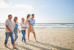 Multi generation family holding hands and walking along the beach together. Caucasian family with two children, two parents and grandparents enjoying summer vacation