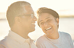 A senior mixed race couple walking together on the beach  smiling and laughing on a day out at the beach. Hispanic husband and wife looking happy and showing affection while having a romantic day on the beach