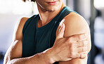 Closeup of one caucasian man holding his sore shoulder while training in a gym. Guy suffering with painful arm injury from fractured joint and inflamed muscles during workout. Struggling with stiff body cramps causing discomfort and strain